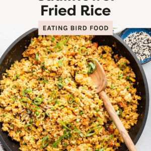 Skillet of Cauliflower Fried Rice with a wood spoon.