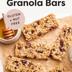 Chewy Granola Bars on parchment paper next to a bowl of honey.