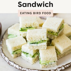 Stack of small, crustless cucumber sandwiches on a rustic plate, ideal for school lunches.