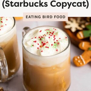 Glass of iced sugar cookie latte topped with whipped cream and festive red and green sprinkles.