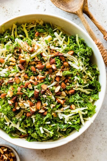 A large bowl of kale crunch salad topped with crushed almonds.