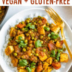 Bowl of rice topped with mattar tofu-- tofu, tomatoes, and peas.