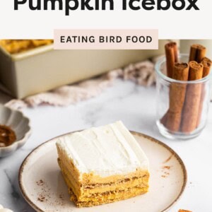 A slice of no-bake pumpkin icebox cake with creamy layers on a plate, surrounded by cinnamon sticks and fall decor.