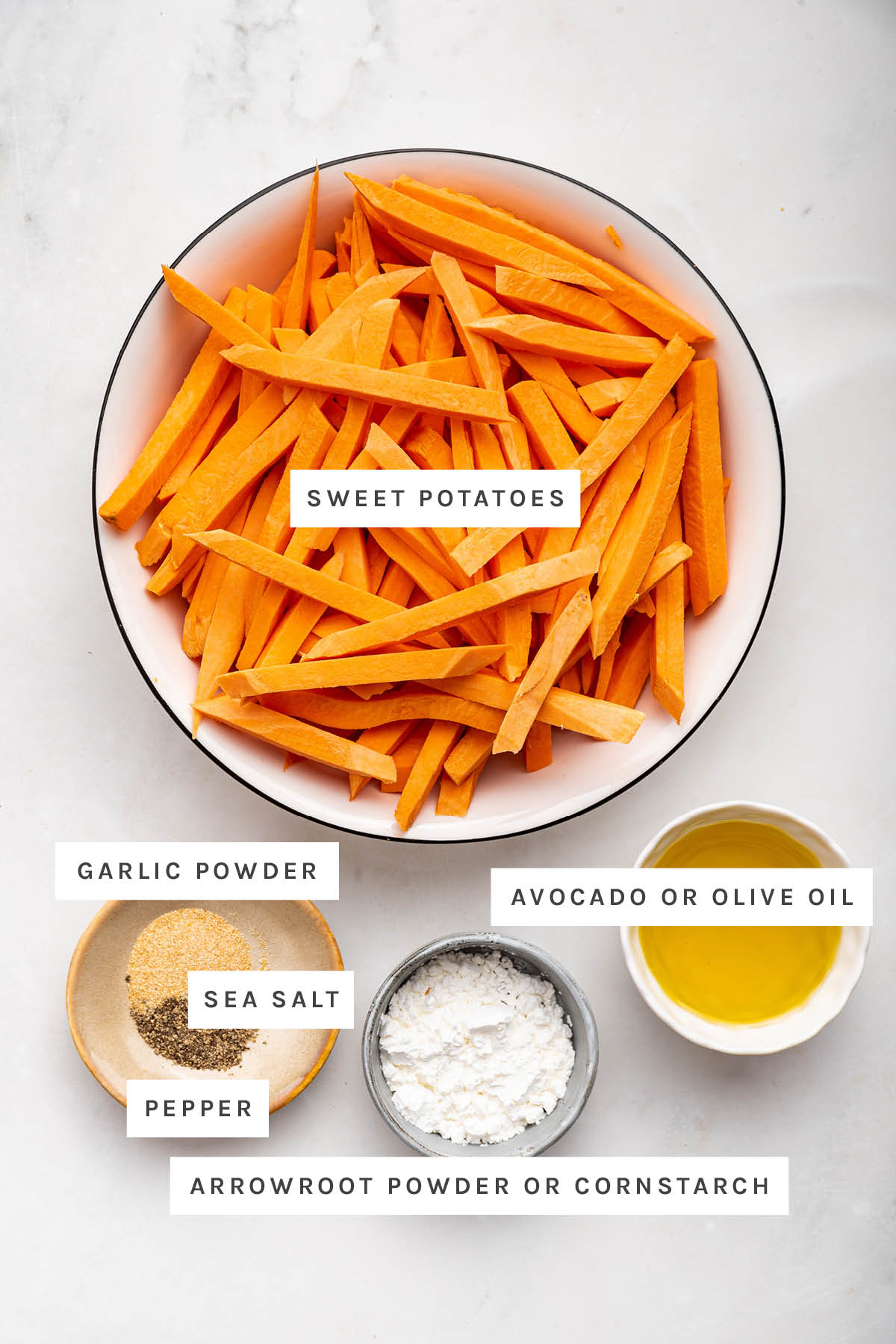 Ingredients measured out to make Baked Sweet Potato Fries: sweet potatoes, garlic powder, sea salt, pepper, arrowroot powder and olive oil.