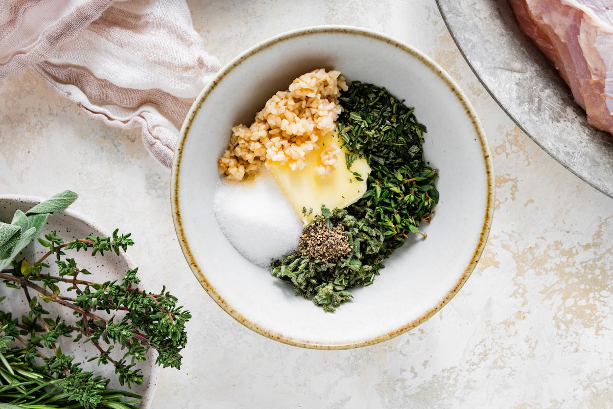 The seasonings, butter and garlic for the air fryer turkey breast in a small white bowl before being mixed together.