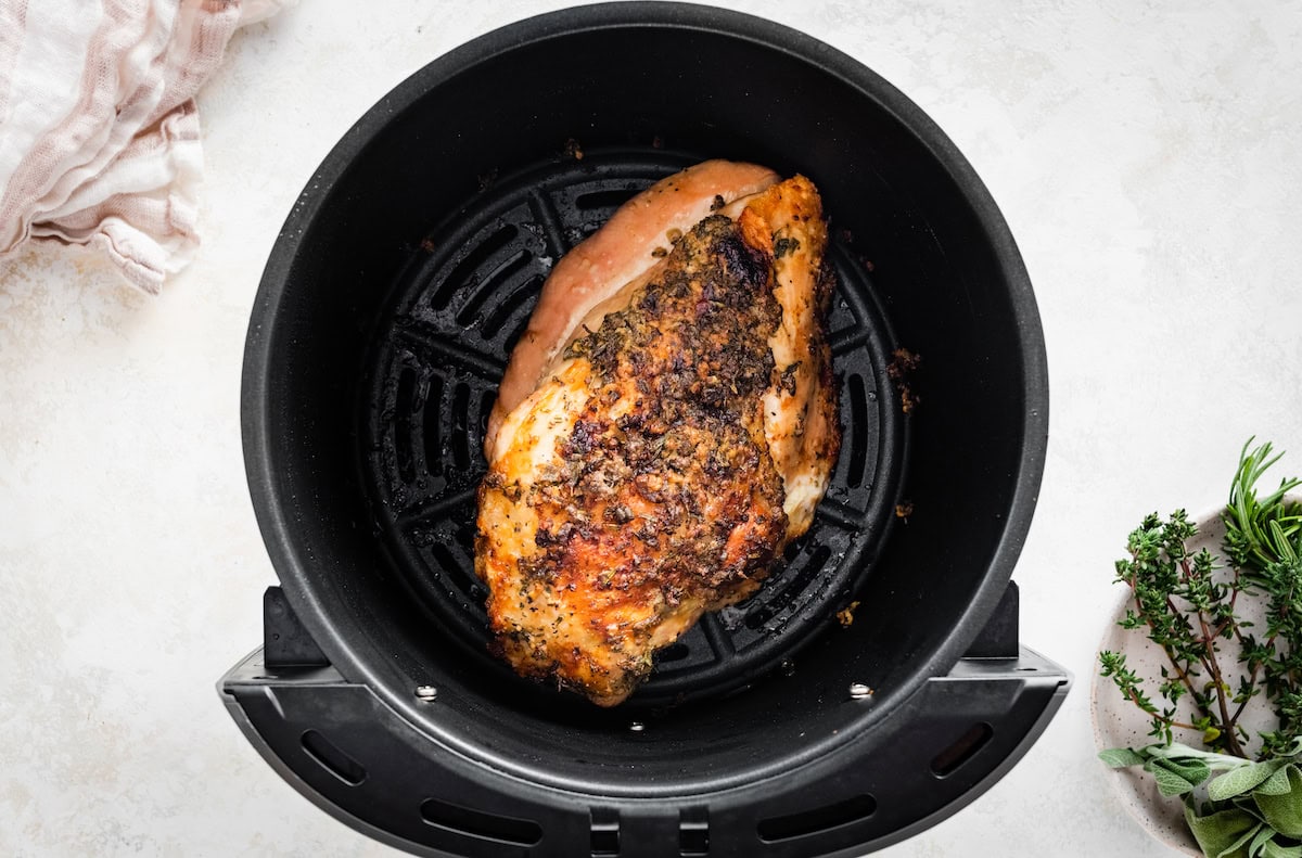 A cooked boneless turkey breast in the basket of an air fryer.