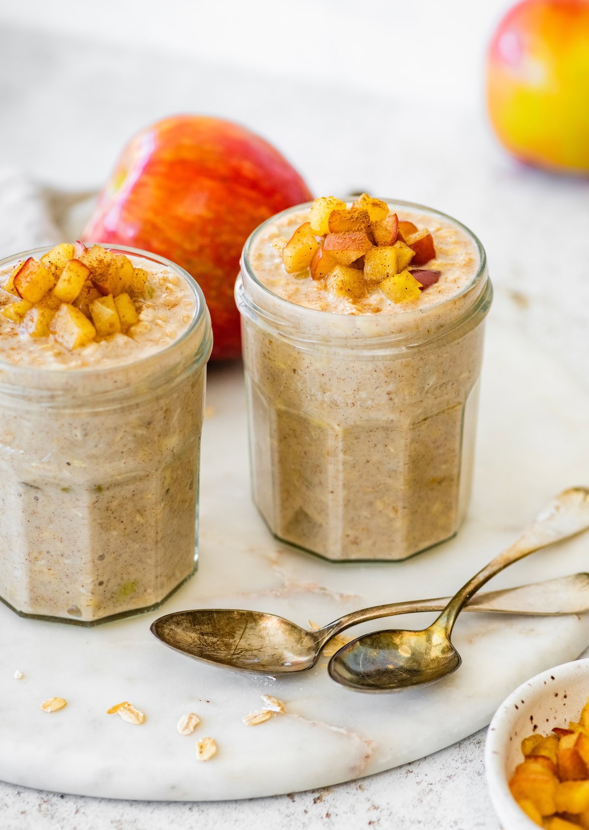 Two jars of apple cinnamon overnight oats topped with diced apples.