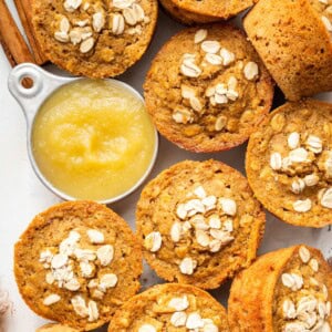 Baked applesauce muffins arranged with a small bowl of applesauce