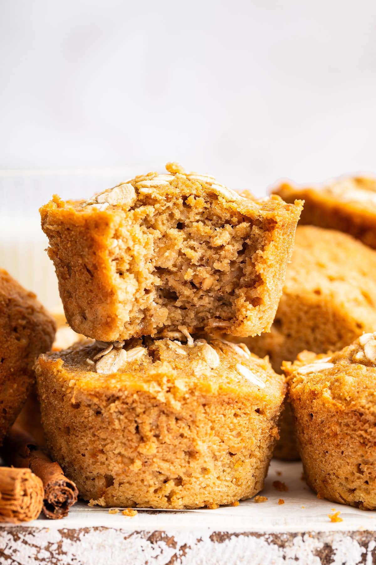 Stack of moist applesauce muffins with a bite taken out to show fluffy interior.