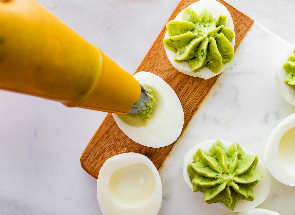 Piping an avocado mixture into the egg.