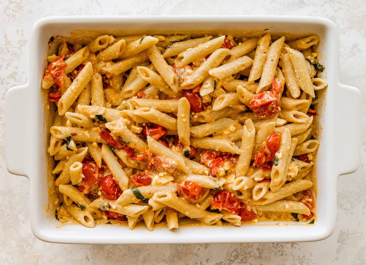 Cooked penne pasta added into the dish with baked feta and tomatoes.