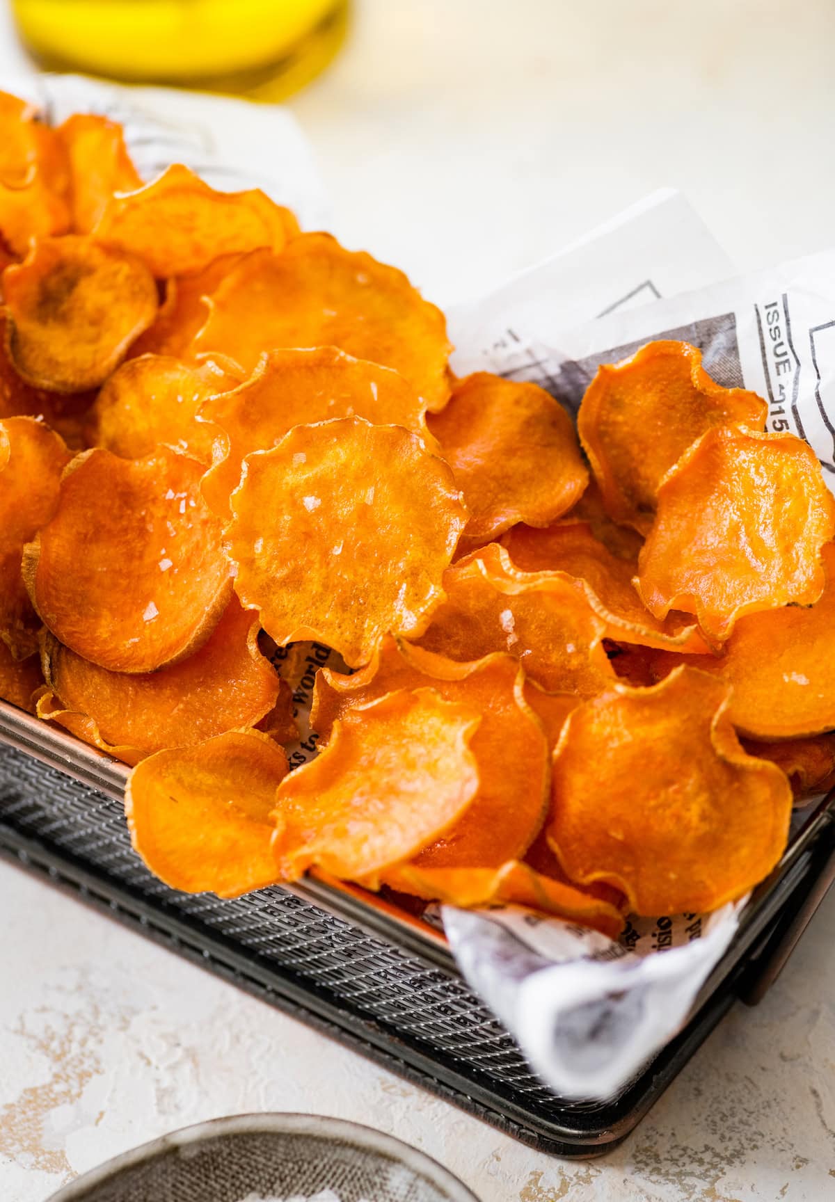 Freshly baked sweet potato chips served in a basket lined with parchment paper.