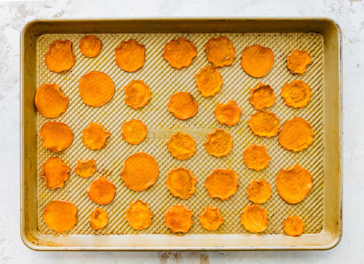 Baked sweet potato slices evenly spaced on a baking sheet.