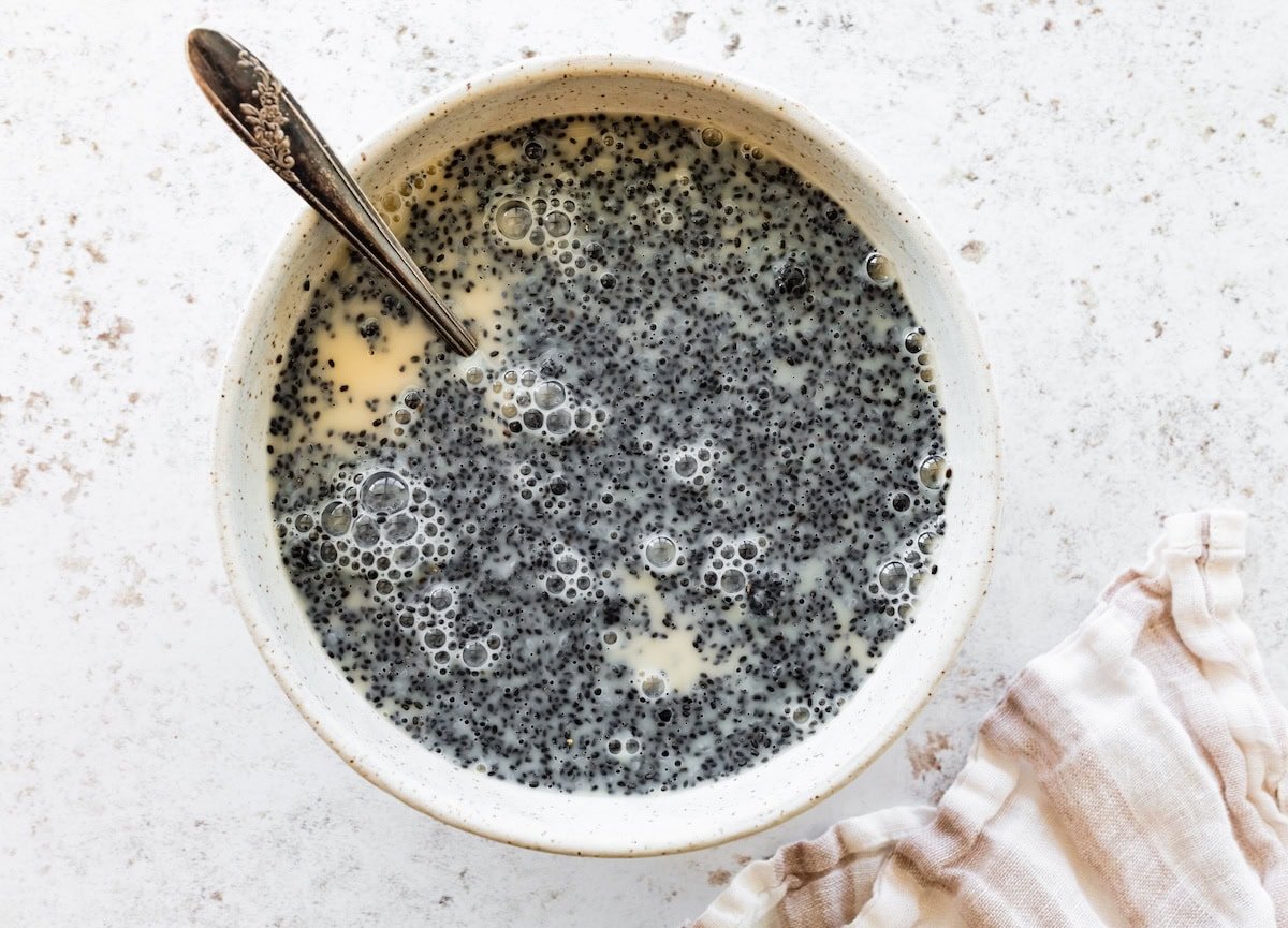 Basil seeds soaking in almond milk and maple syrup in a mixing bowl.