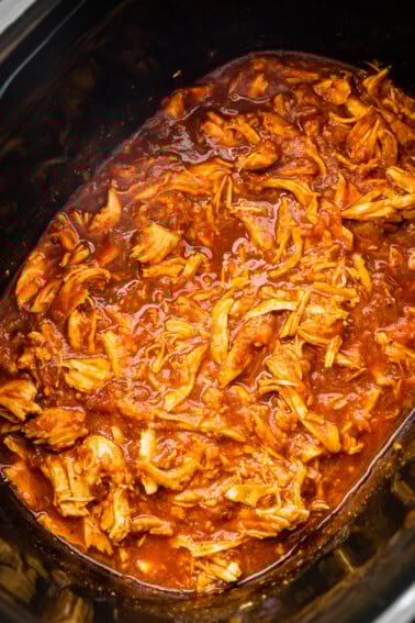 A slow cooker pot full of bbq shredded chicken.