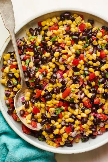 Serving bowl with black bean and corn salad. Spoon is in the bowl.
