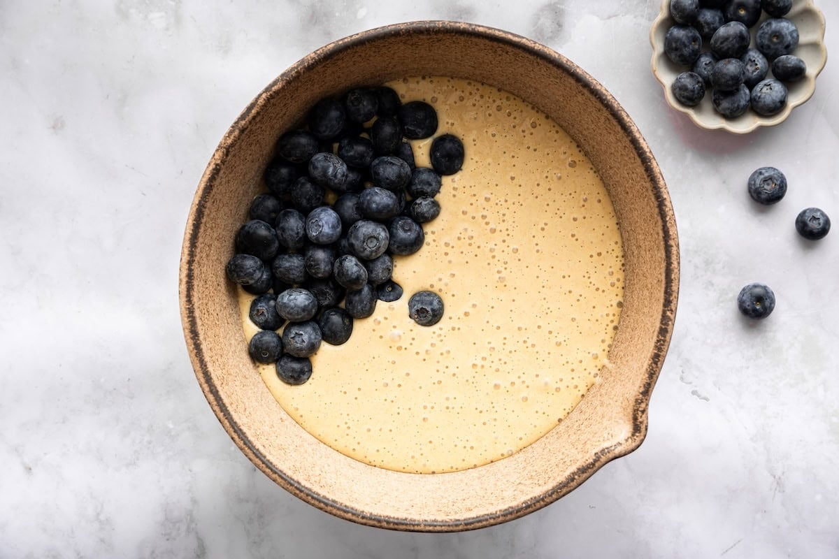 Blended batter for blueberry cottage cheese breakfast bake in a bowl with fresh blueberries on top.