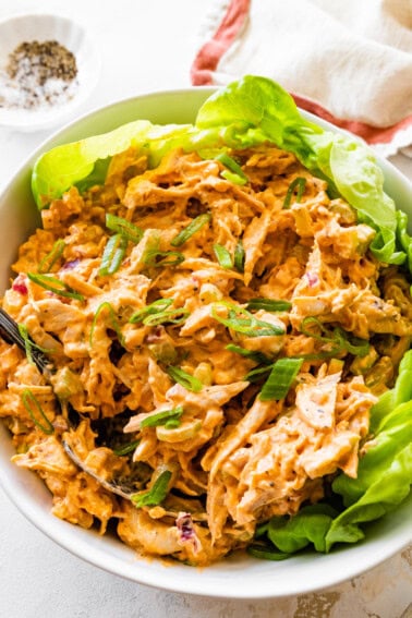 A bowl with buffalo chicken salad on a bed of lettuce.