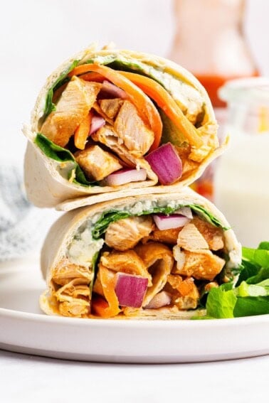 Buffalo chicken wrap halves stacked on top of each other with chicken, carrots, and onion inside.