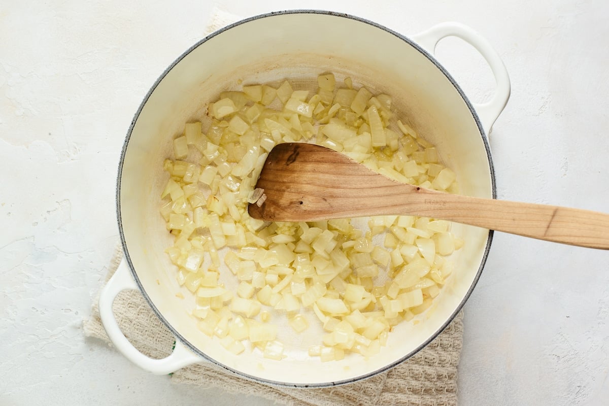 A large pot with sautéed onions and garlic.