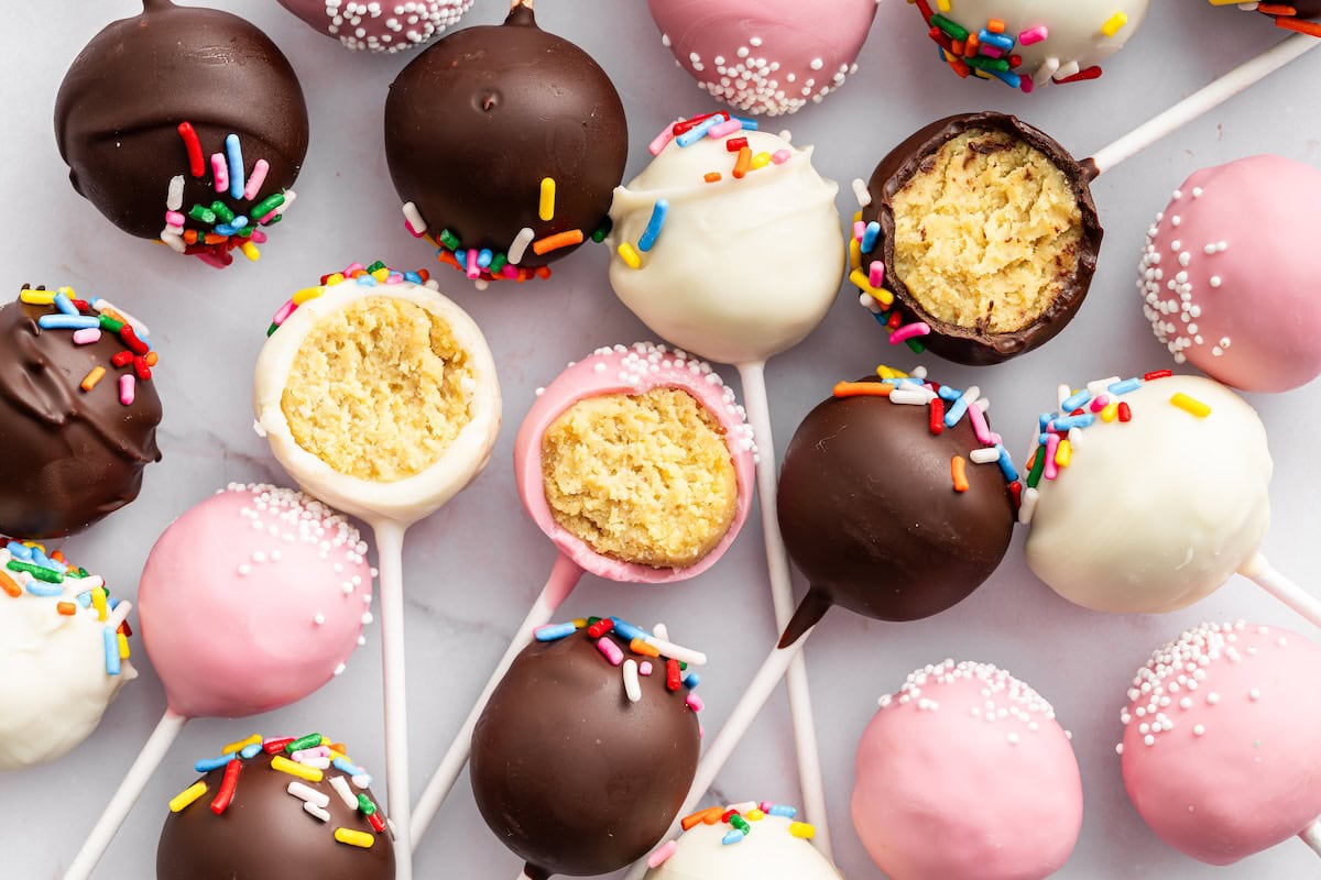 Chocolate, pink, and white cake pops decorated with sprinkles.