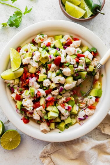 A large white bowl of ceviche with fresh fish, avocado, tomato, cucumber, and avocado.