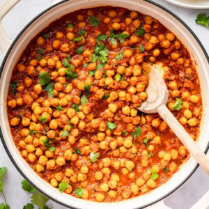 Chickpeas simmering in spiced tomato sauce in a large pot of chana masala.