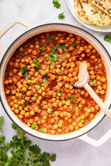 Chickpeas simmering in spiced tomato sauce in a large pot of chana masala.
