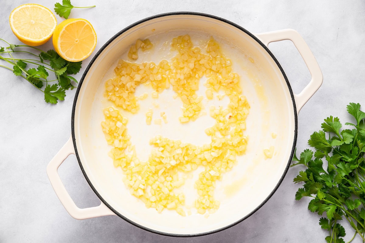 Garlic, onion and ginger sautéing in a large white skillet.