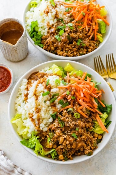 Chicken lettuce wrap bowl with cauliflower rice, shredded carrots, and peanut sauce on the side.
