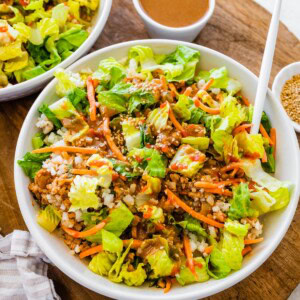 Chopped salad version of chicken lettuce wrap bowl with lettuce, cauliflower rice, carrots, and peanut sauce.