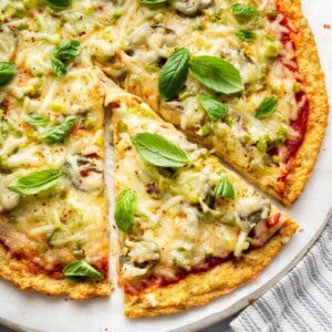 Chicken crust pizza topped with melted mozzarella and basil leaves.