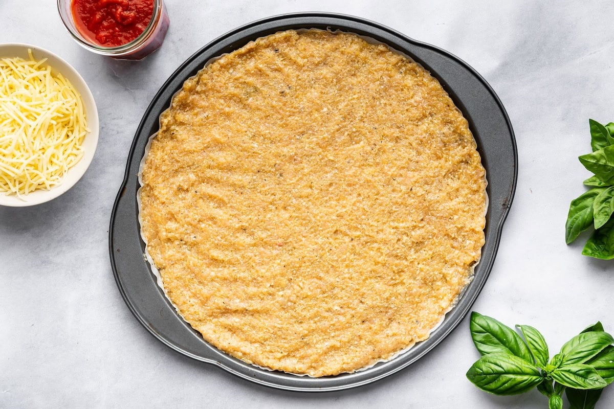 Freshly baked low-carb chicken pizza crust on a round pan.