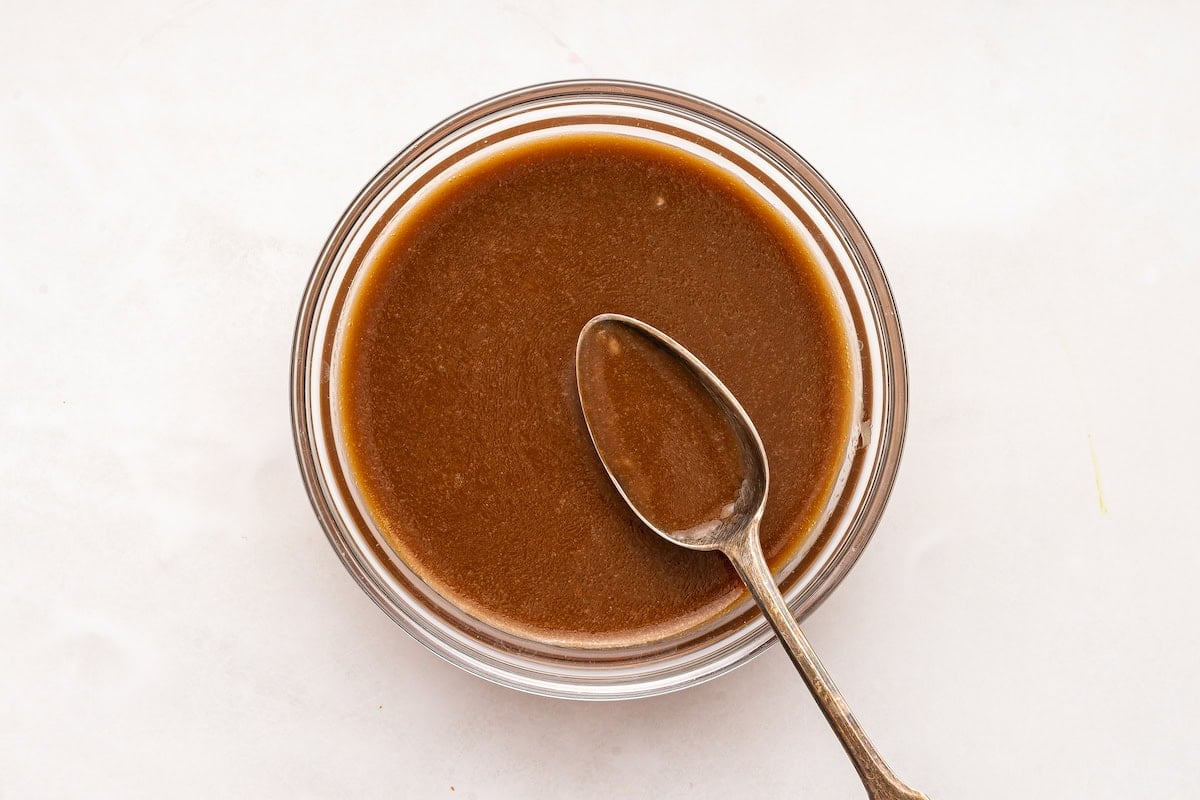 The combined balsamic dressing in a small glass container with a silver spoon.