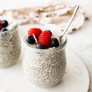Coconut chia pudding in a glass cup, topped with fresh berries.