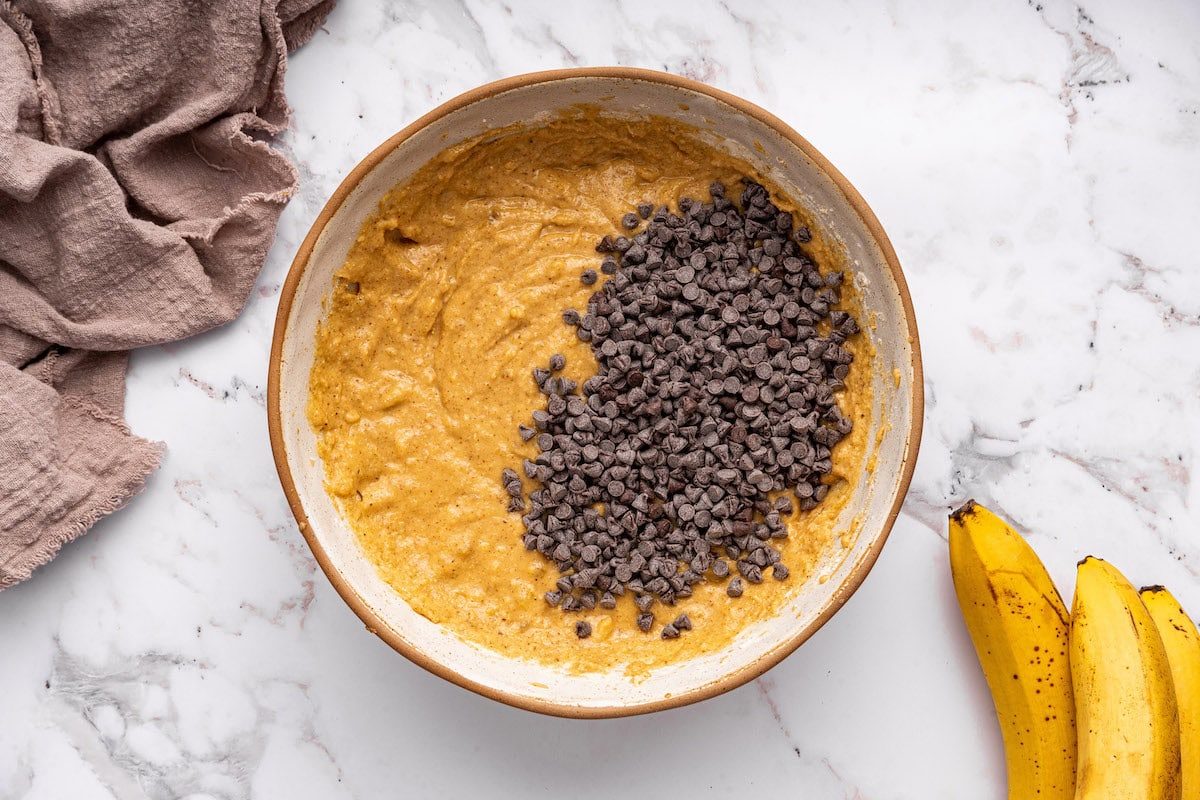 Chocolate chips added to a large bowl of coconut flour banana bread batter.