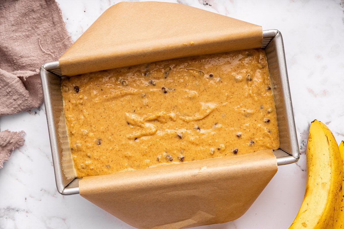 Coconut flour banana bread batter with chocolate chips added to a bread pan.