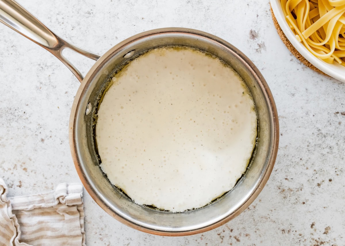 Cottage cheese Alfredo sauce warming in a saucepan with a smooth, creamy texture.