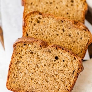 Three thick slices of banana bread stacked on white parchment paper.