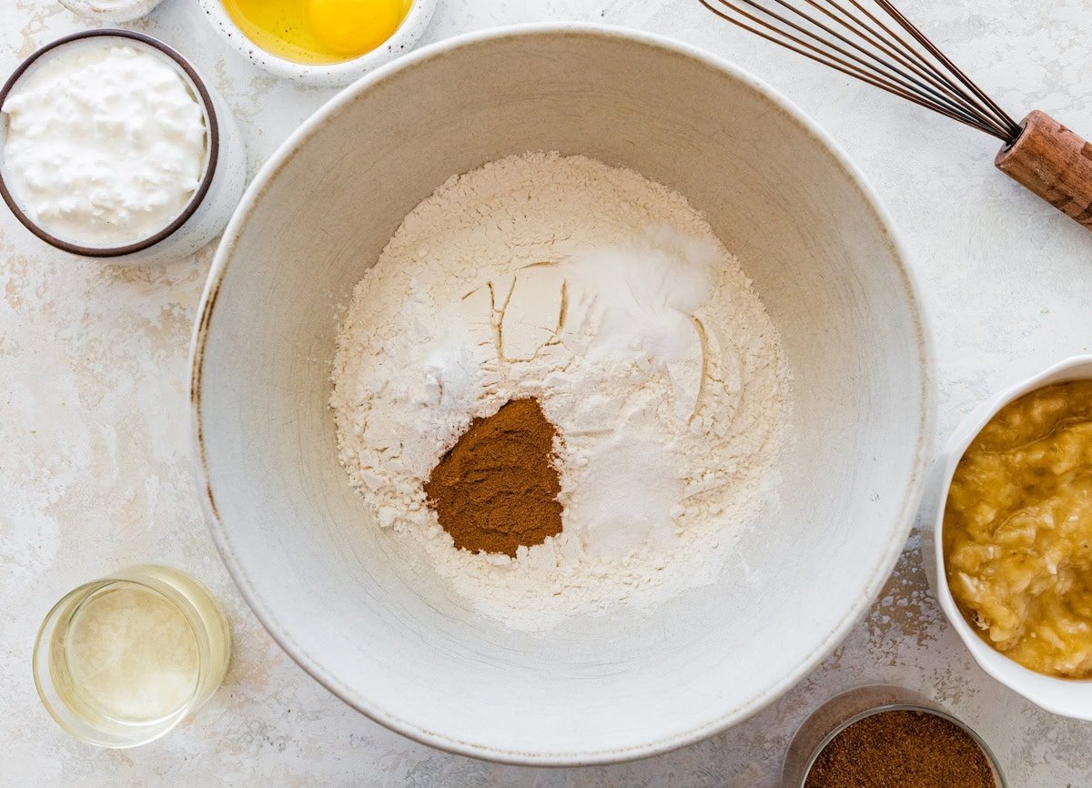 Mixing bowl with flour, cinnamon, and dry ingredients for banana bread.