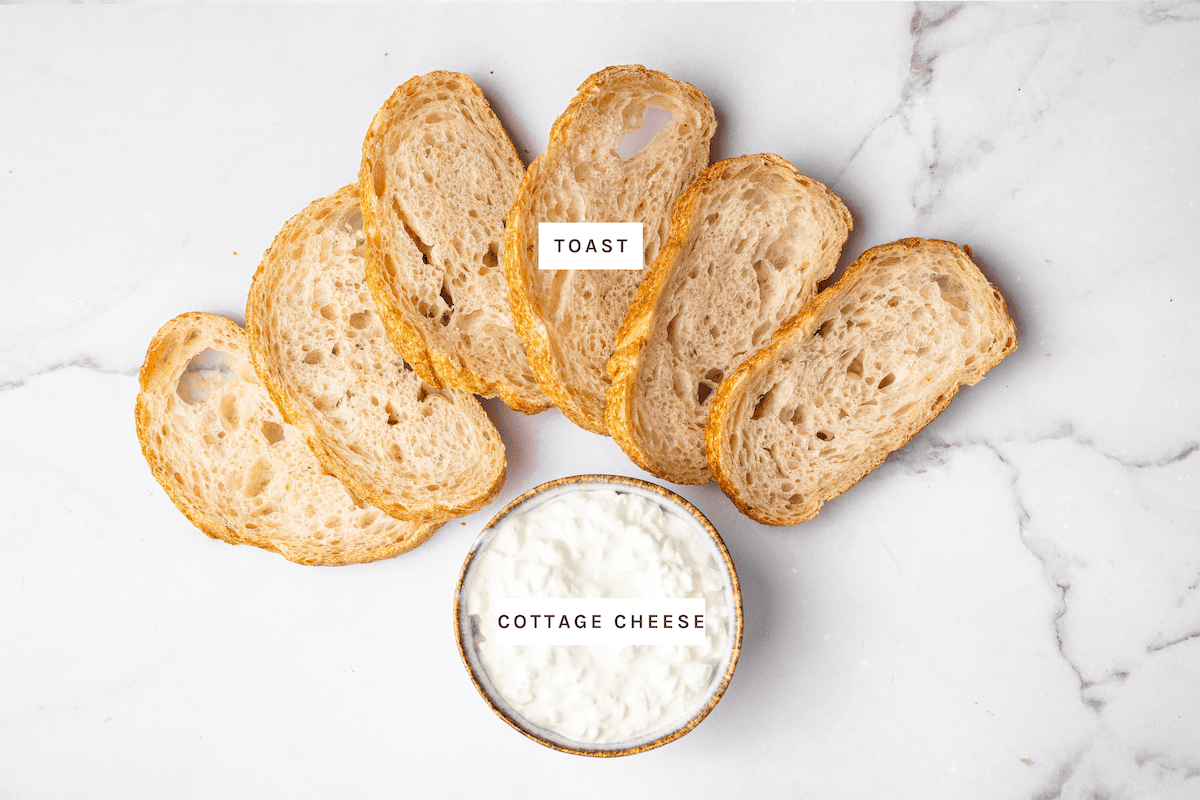 Base ingredients for cottage cheese toast including toasted sourdough bread slices and a small bowl of cottage cheese on a white background.