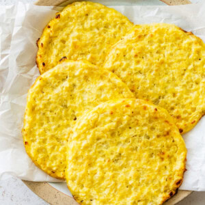Four cauliflower thins on a plate line with parchment paper.