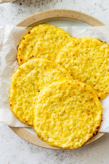 Four cauliflower thins on a plate line with parchment paper.