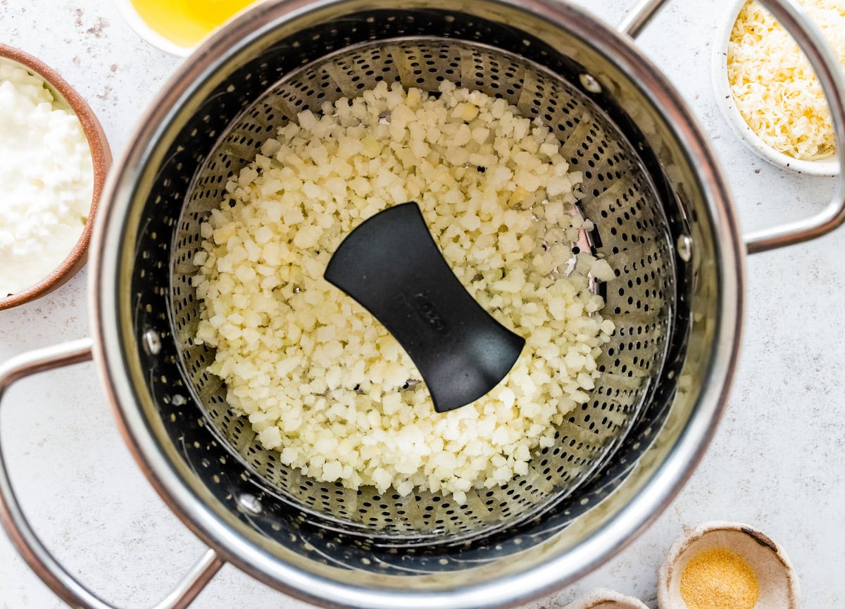 Steamed cauliflower rice in a colander.