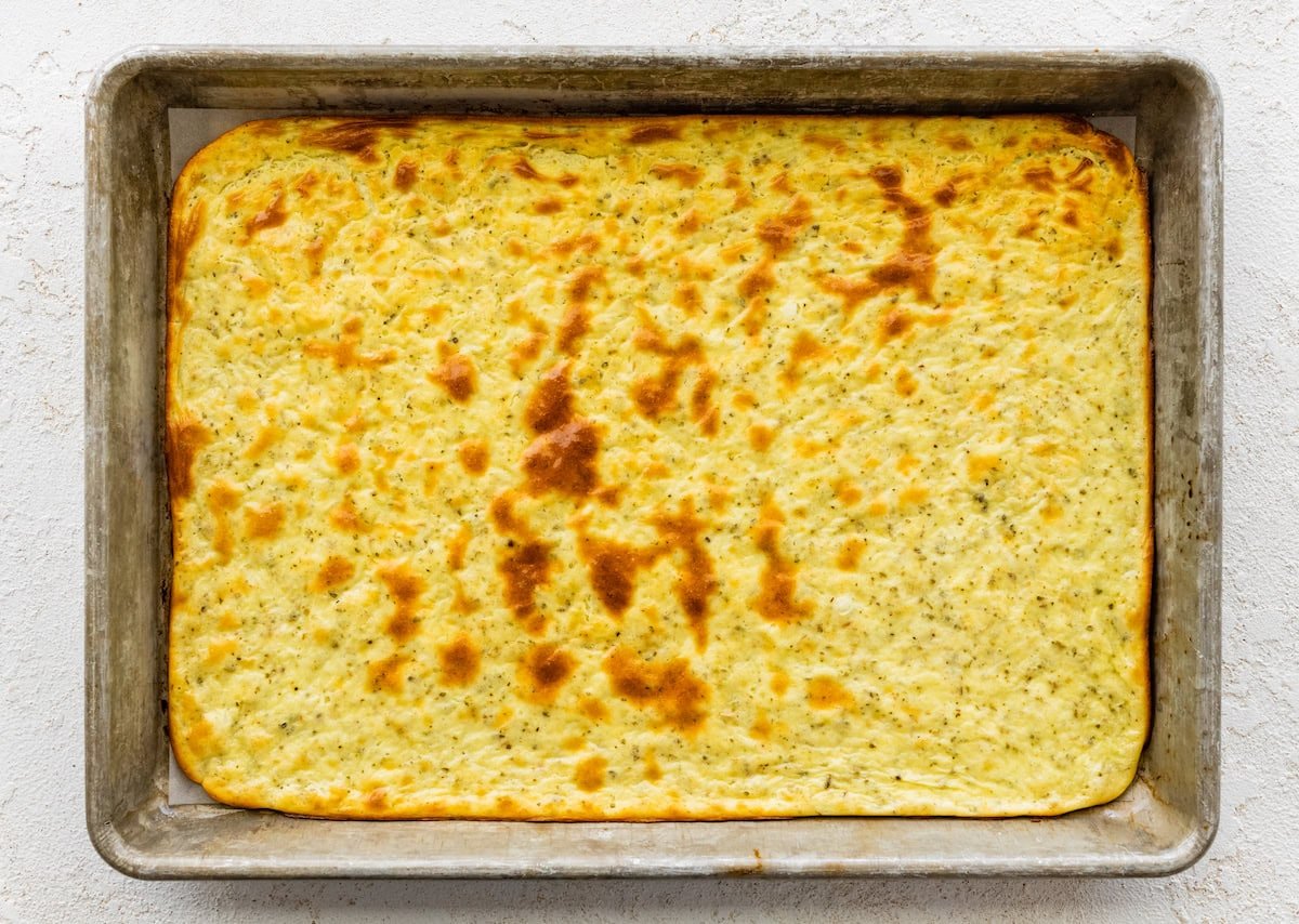 A baked cottage cheese flatbread on parchment paper on a small baking tray.