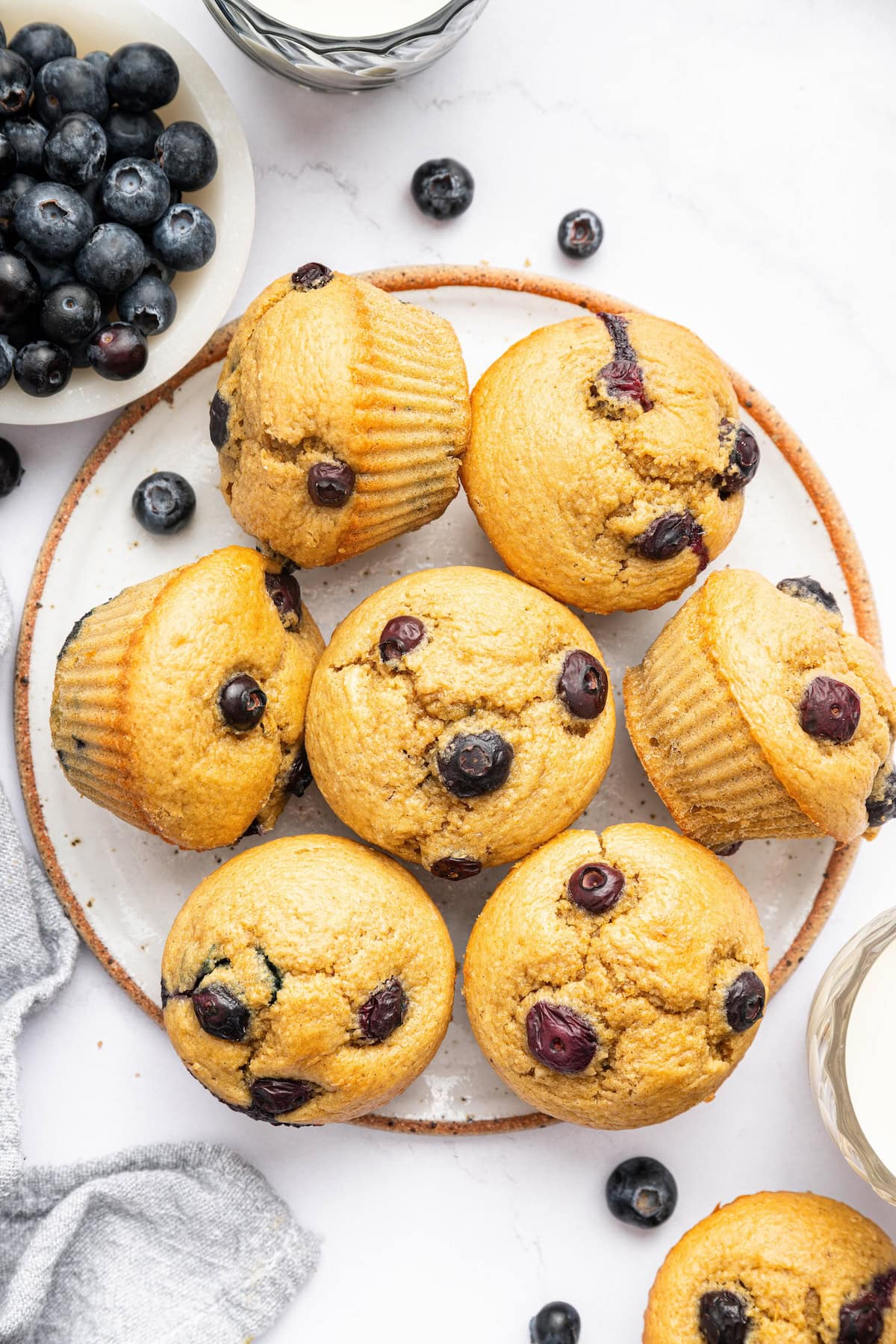 Seven cottage cheese blueberry muffins on a plate. Three of the muffins are on their side.