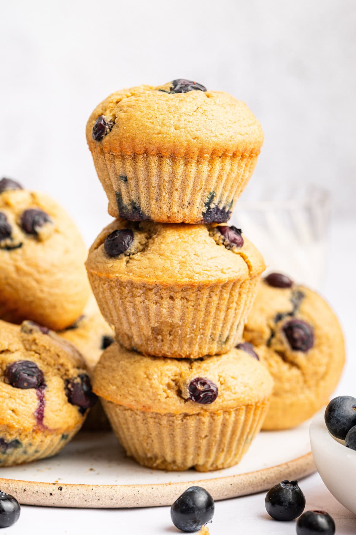 Three blueberry cottage cheese muffins stacked on top of each other with more muffins in the background.