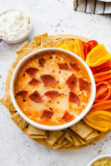 Cottage cheese pizza bowl topped with melted mozzarella and turkey pepperoni, served with mini bell peppers and whole-grain crackers for dipping.