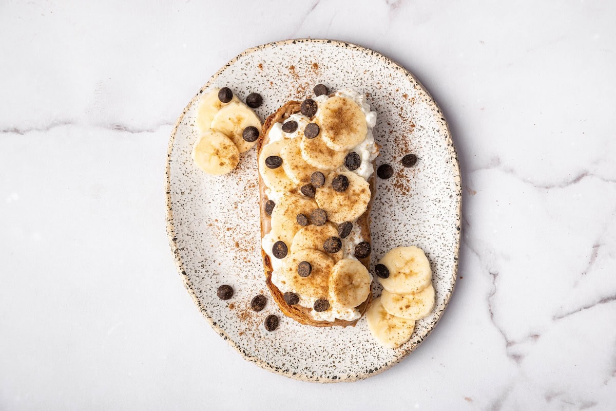 Cottage cheese toast topped with sliced banana, mini chocolate chips, and a sprinkle of cinnamon.