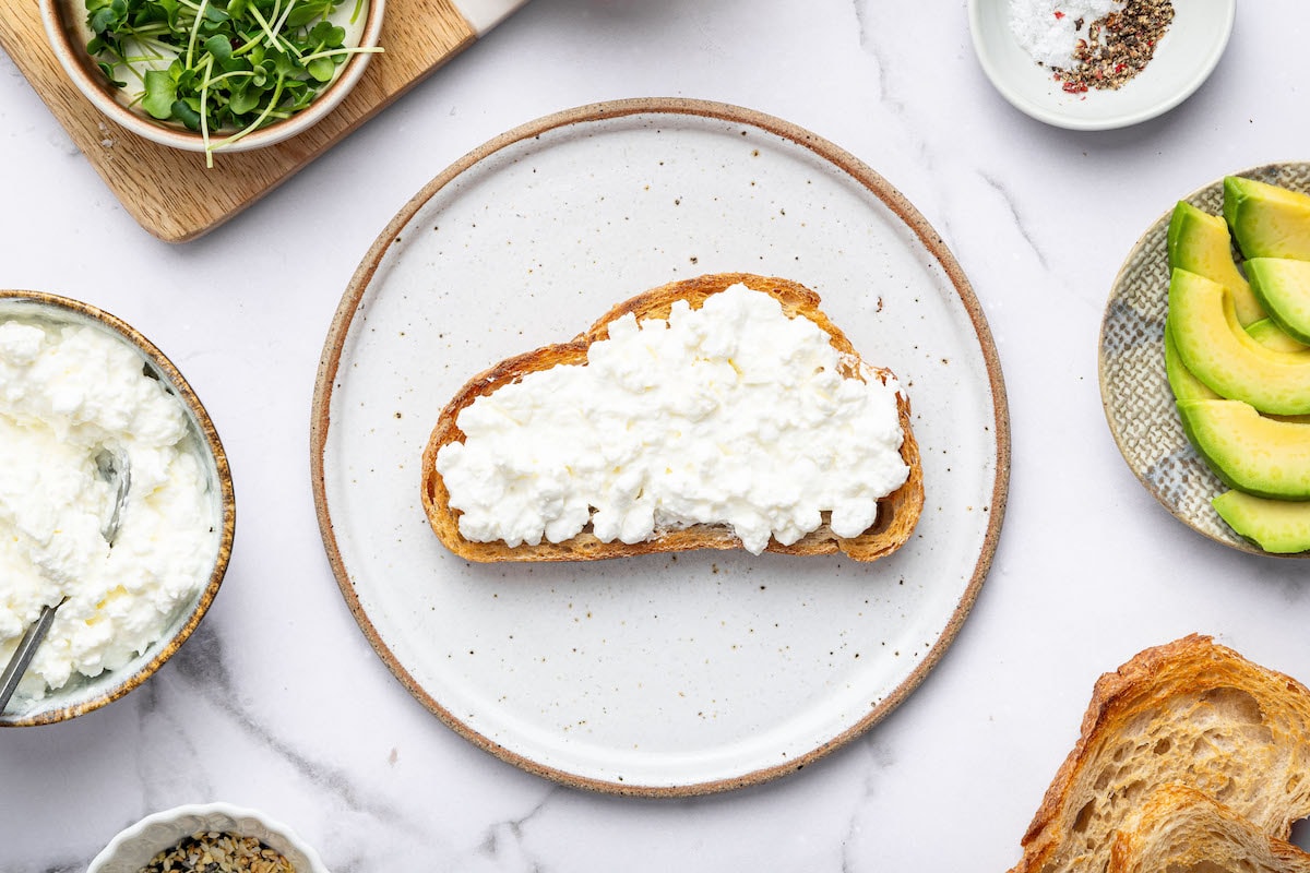 Slice of toasted sourdough bread spread with creamy cottage cheese.